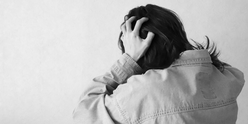 白黒画像で背を向けた人が頭を抱えている