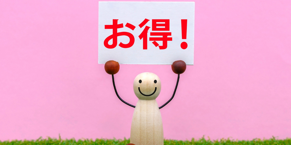 “地域密着”の文字が書かれた木製ブロックと観葉植物が並ぶデスクの上の風景。地元に根ざしたサービスの象徴