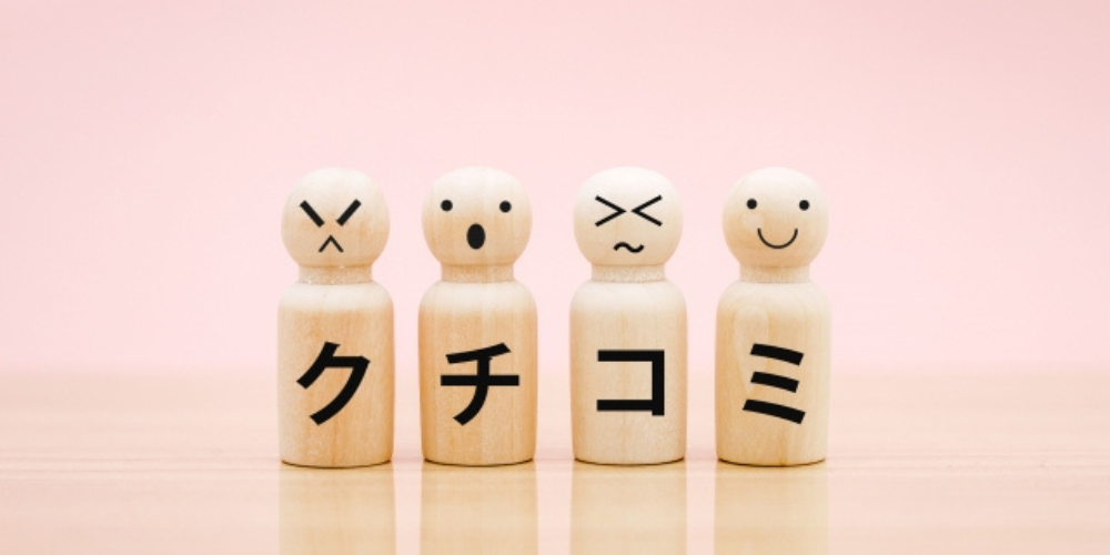 表情の異なる木製人形4体に『クチコミ』の文字が書かれたピンク背景の構成