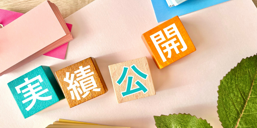 「実績公開」と書かれた木のサイコロと、付箋紙