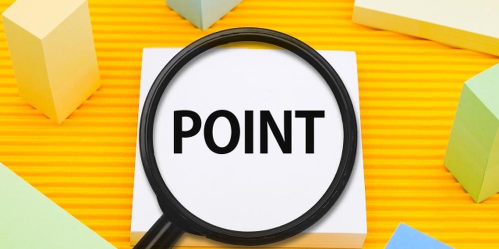拡大鏡で「POINT」という文字が強調されているメモ用紙とカラフルな立方体の小物