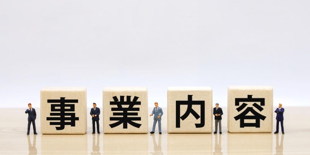 事業内容の文字ブロックとスーツ姿のミニチュア男性たち