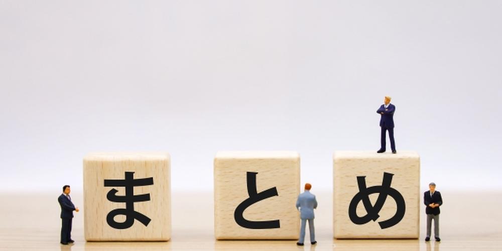 「まとめ」と書かれた積み木の上に小さなスーツ姿のフィギュア