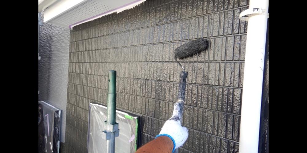 外壁に黒い塗料を塗る作業