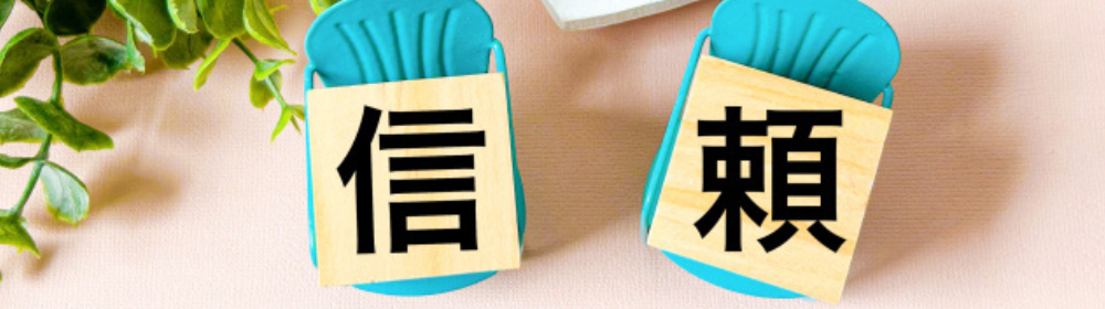 青い椅子に置かれた木のブロックに「信」「頼」と書かれた文字が並んでいる