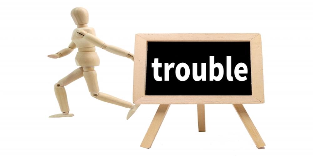 　『trouble』と書かれた黒板と逃げるような姿勢の木製人形