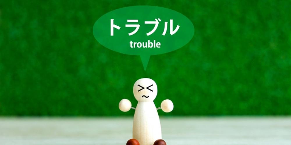 緑の背景に「トラブル（trouble）」と書かれた吹き出し