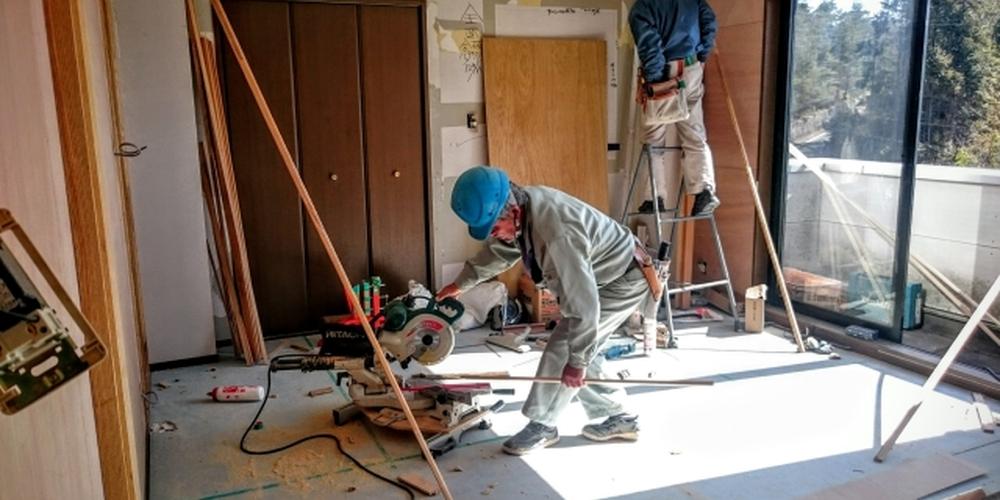 室内でリフォーム作業を行う職人たち、電動工具を使った木材加工の様子