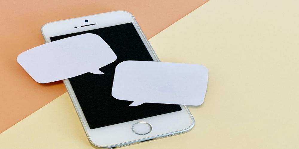 スマートフォンの上に吹き出し型の白紙メモが置かれたイメージ。ビジネスでの対話や意見交換、アイデアの可視化を示唆するビジュアル。