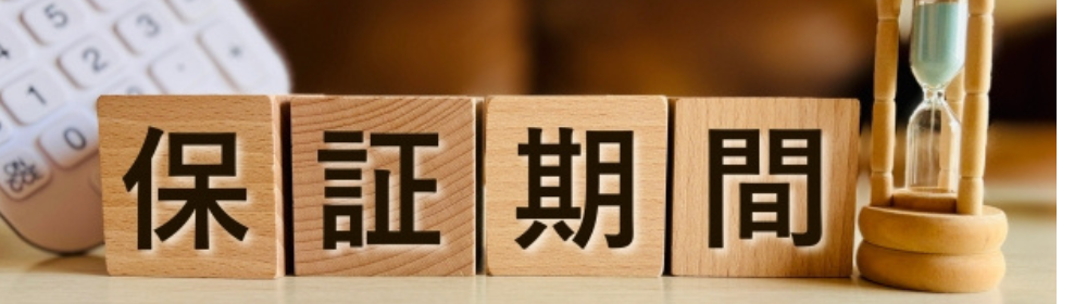 「保証期間」と書かれた木製ブロックと電卓、砂時計が並ぶイメージ