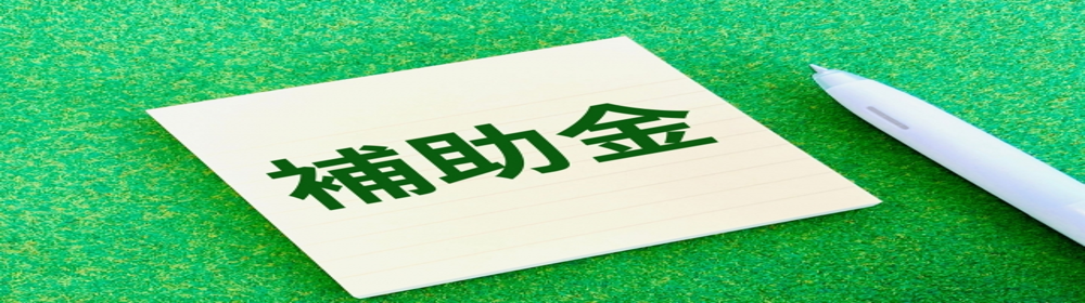 補助金と書かれたメモ用紙とペン　緑背景