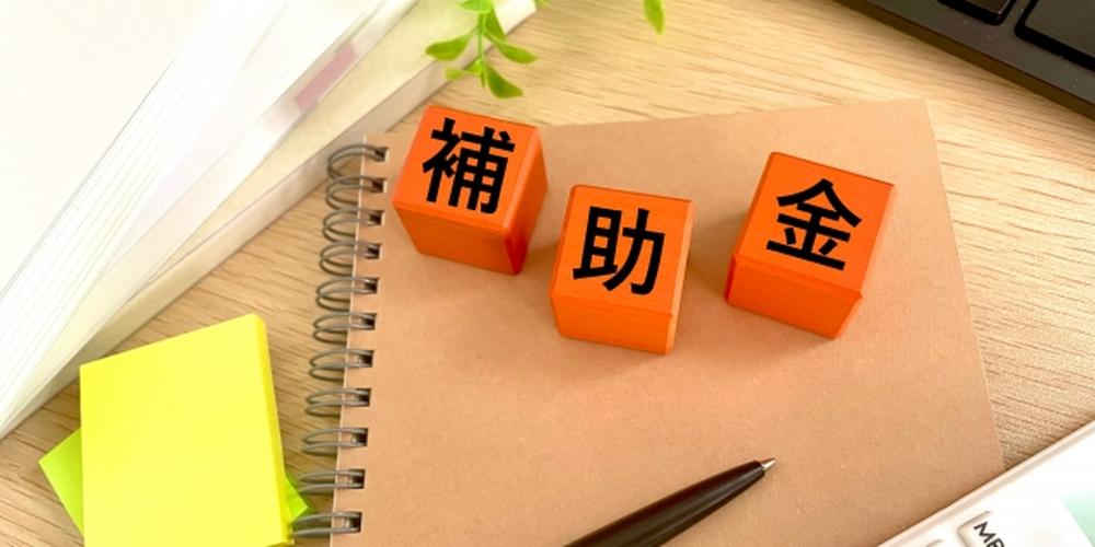 ノートの上に「補助金」と書かれた3つのブロック