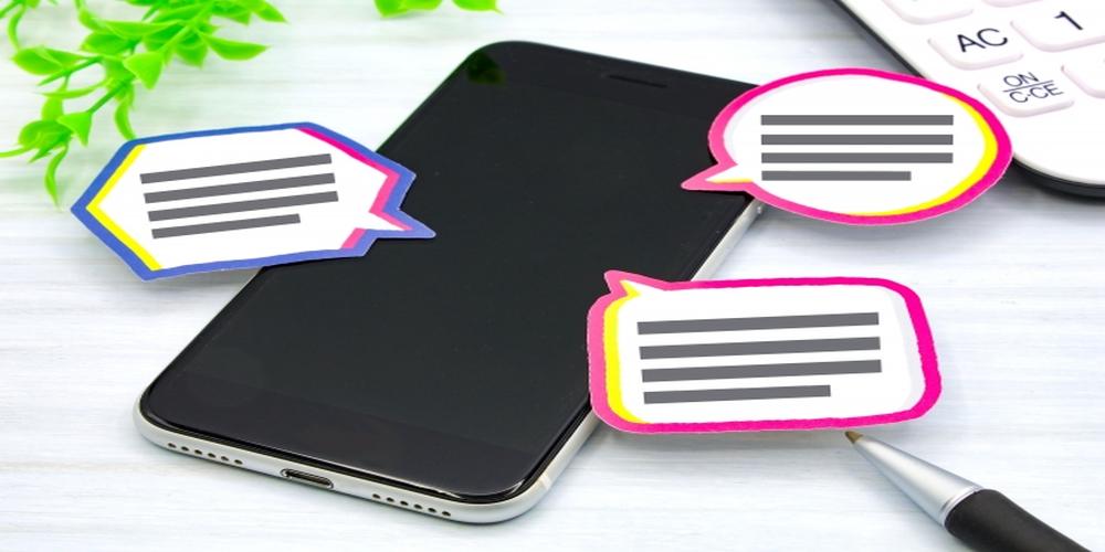 スマートフォンの周りに吹き出し型のメモが置かれたデスク
