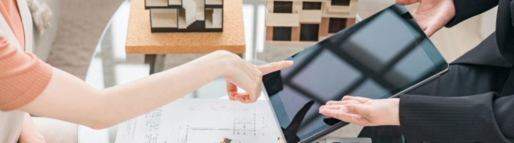 住宅模型と資料を前に、タブレットで相談をする顧客と担当者の打ち合わせ風景