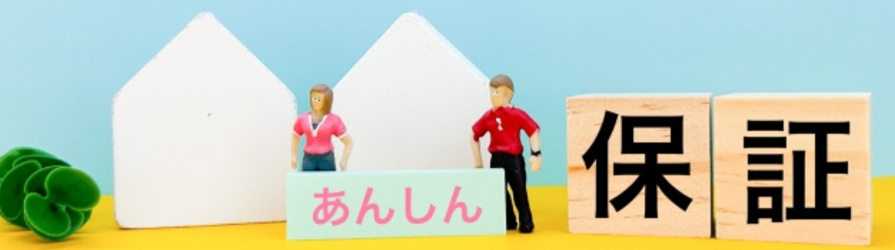 『あんしん』のプレートを持ったミニチュアの男女と『保証』の文字ブロック、家の模型