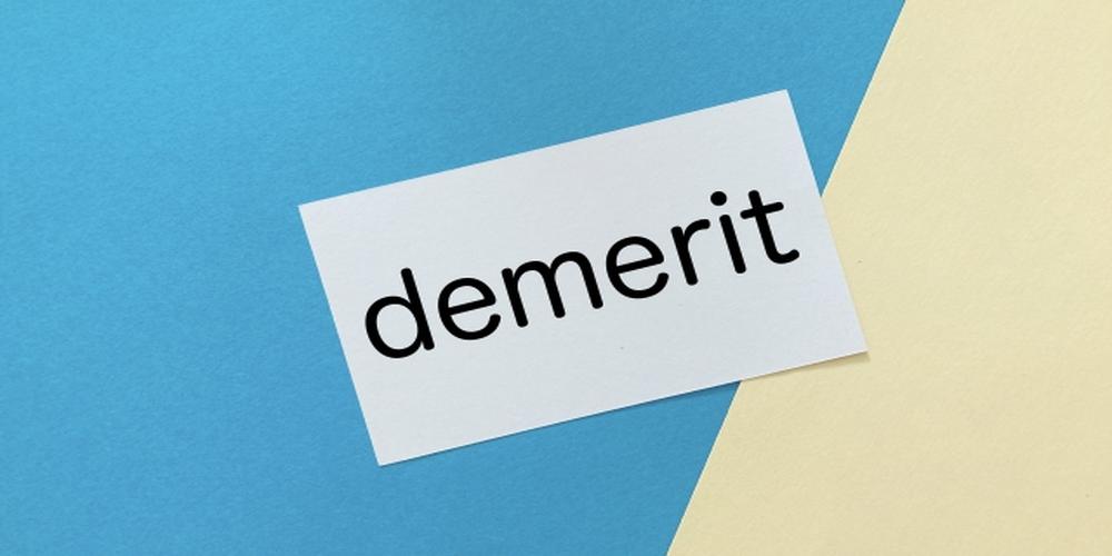 “demerit”と書かれたカードが青とベージュの背景の上に配置されたイメージ。課題や注意点をシンプルに表現したビジュアル。