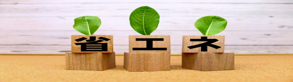 “省エネ”と書かれた木製ブロックに若葉が添えられたイメージ。エネルギー効率や環境配慮を象徴