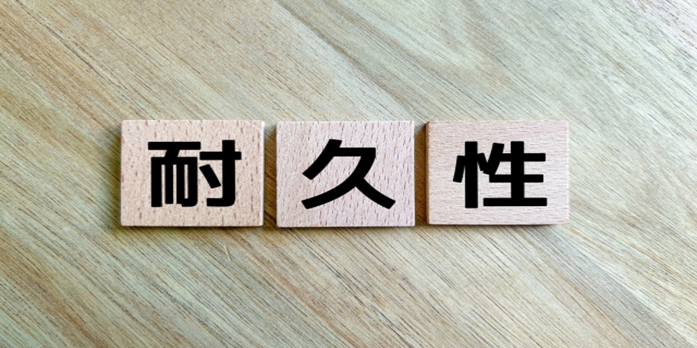 “耐久性”の文字が記された木製ブロック。信頼性や長期的視点での投資価値を象徴する構図