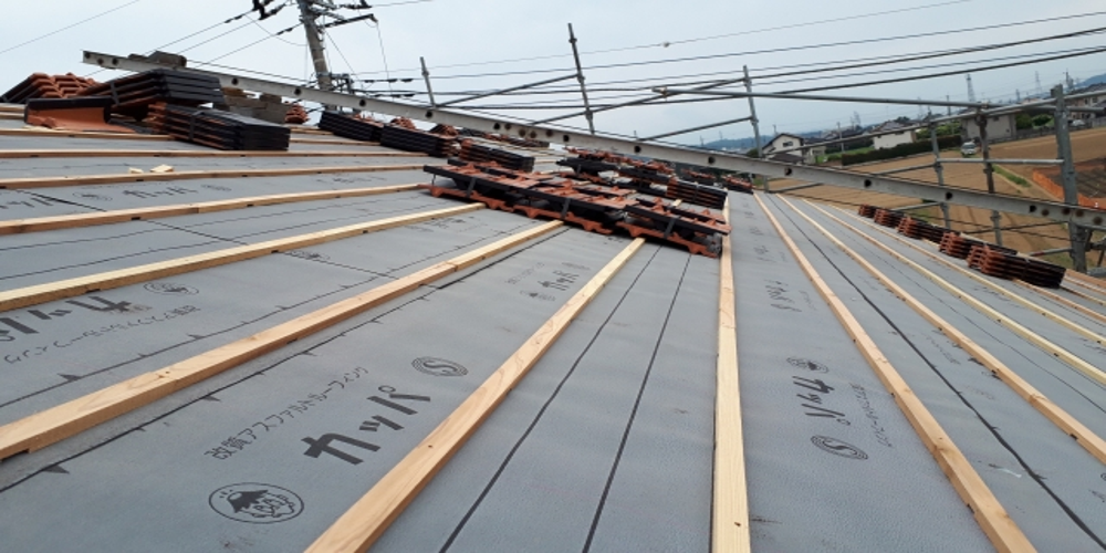 屋根工事中の建物。防水シートと桟木が設置され、瓦の準備が整った状態の屋根作業現場