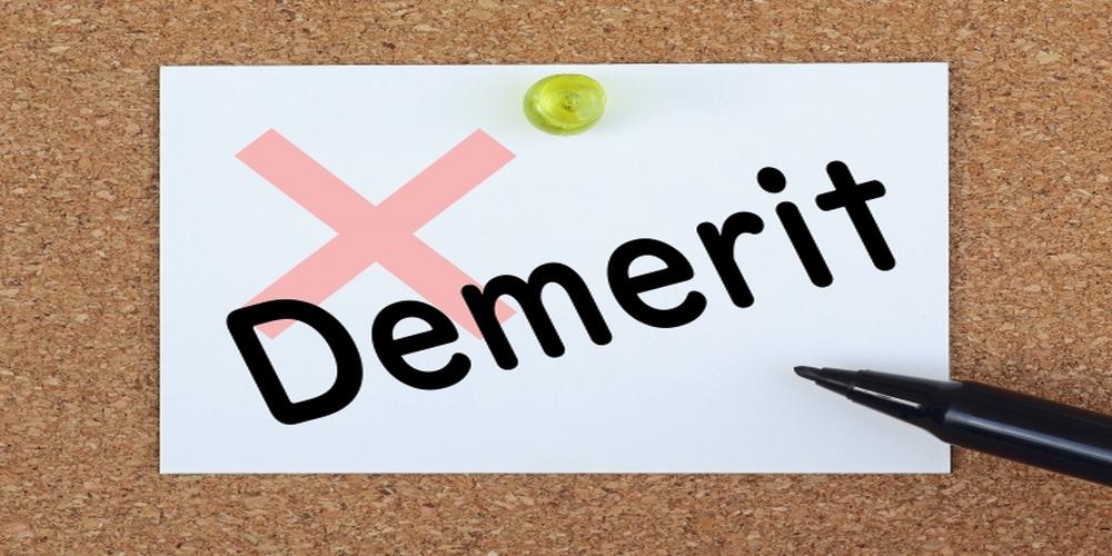 “Demerit”と書かれたメモがコルクボードにピンで留められ、赤いバツ印とペンが添えられたイメージ。リスクや懸念点を明確に伝えるビジュアル。