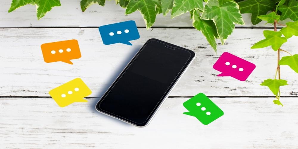 スマートフォンの周囲にカラフルな吹き出しが表示された画像。問い合わせやチャット対応など、顧客とのコミュニケーションを象徴するビジュアル。