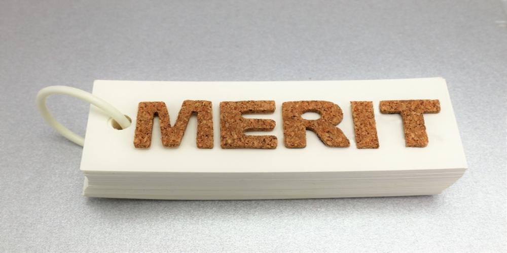 “MERIT”の文字がコルク素材で作られた単語カードに配置されたイメージ。ビジネスにおける利点や価値をナチュラルかつ印象的に伝えるビジュアル。