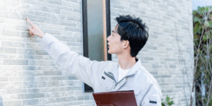 外壁を指差しながら点検する建築技術者