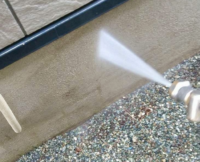 壁を高圧洗浄する様子